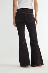 Jean de corte flare en color negro, con costuras verticales decorativas en contraste y ruedo deshilachado.