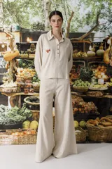 Pantalón de tiro alto, pierna ancha y largo, color beige claro con finas rayas verticales en tono oscuro. Presenta un diseño de cinco bolsillos estilo jean.