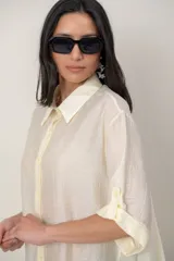 Camisa oversize de seda negra, con cuello camisero, cierre frontal con botones y mangas cortas con vuelta.