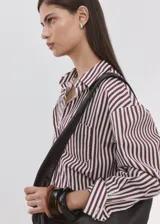 Camisa de corte recto confeccionada en mezcla de algodón y poliéster, con estampado de rayas. Cuenta con cuello camisero, manga larga con puños abotonados, bolsillo de parche en el pecho y cierre frontal con botones.
