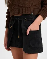 Minifalda de cuero negro con silueta recta y diseño de capas frontales superpuestas. Presenta un lazo ajustable en la cintura que pasa por ojalillos metálicos y bolsillos frontales aplicados.