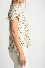 Remera color crema con estampado de manchas marrones, de corte oversize, con cuello en V y mangas cortas.