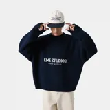 Sweater de punto grueso color azul marino, con cuello redondo, corte cuadrado y ligeramente corto. Presenta gráficos de "EME STUDIOS curated by bien ice" en jacquard blanco en el frente. Tiene puños ajustados.