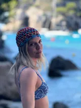 Gorro tipo beanie tejido a crochet con patrón calado, en combinación de tonos rojo, azul, terracota y marrón.