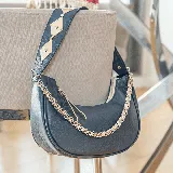 Cartera bandolera negra de cuero vacuno con cierre superior y forro interior de tela. Incluye dos correas cortas para usar al hombro (una de cuero y otra de cadena dorada) y una correa larga ajustable y removible para usar como morral.