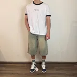 Bermuda de jean con corte baggy y largo por debajo de la rodilla, en tono azul claro lavado con efecto desgastado.