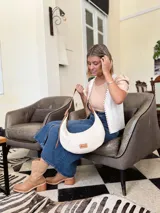 Cartera tipo hobo de cuero color crudo con correa de cuero marrón.