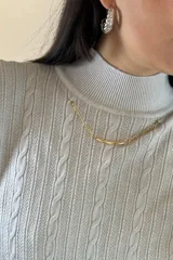 Buzo de hilo de punto con diseño de trenzas verticales, cuello alto y cadena metálica decorativa incorporada en la parte frontal.