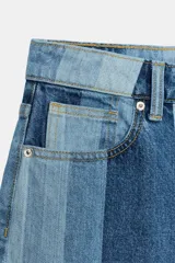 Jeans de tiro medio y pernera recta con diseño de rayas verticales en diferentes tonos de denim. Cuenta con cinco bolsillos y cierre frontal con cremallera y botón.