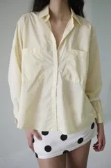 Camisa de rayas verticales rosadas y celestes, con cuello clásico, botonadura frontal y doble bolsillo delantero. Tiene un calce relajado y terminación curva en el ruedo.