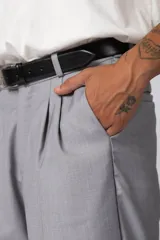 Pantalón sastrero de corte baggy, color beige, con pinzas frontales, cierre de botón y cremallera, y bolsillos laterales.