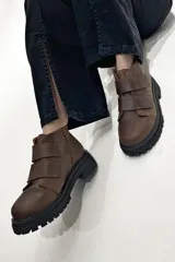Botas marrones de cuero con suela track negra y ajuste con dos tiras de velcro.
