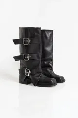 Botas de caña media en cuero negro, con diseño holgado y tres correas horizontales con hebillas metálicas ajustables. Poseen taco cuadrado bajo y punta redondeada.