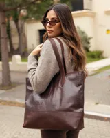 Bolso tipo tote de cuero vacuno color chocolate, con textura efecto cocodrilo en la parte superior y base lisa. Cuenta con doble asa de hombro y cierre superior.