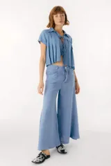 Pantalón blanco de lino, corte palazzo, con bolsillos laterales y cierre frontal con botón.