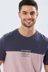 Remera de algodón y poliéster de corte clásico, con diseño en bloques de color negro en la parte superior y gris melange en la inferior. Presenta cuello redondo, mangas cortas y un pequeño estampado tipográfico en el pecho.