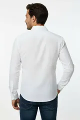 Camisa blanca de algodón, de corte slim fit, con cuello camisero, manga larga y cierre frontal de botones.