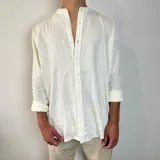 Camisa de manga larga en tejido de lino, color blanco, con cuello mao y cierre frontal de botones. Presenta un corte oversize y mangas con puños doblados.