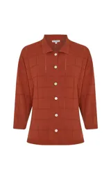 Camisa de punto de algodón color terracota con diseño a cuadros texturizados, cuello solapa, cierre frontal de botones y mangas cortas.