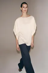 Top fluido de manga corta de Zara Woman Collection, confeccionado en hilatura de viscosa de color crudo. Cuenta con cuello barco, bajo recto y cierre en la espalda con pequeña abertura y botón.