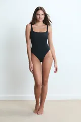 Body de diseño minimalista en color negro, con escote cuadrado y tirantes anchos. Presenta un corte de pierna alto y espalda descubierta, confeccionado en tejido elástico de acabado suave.