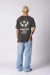 Remera negra con efecto acid wash, corte oversize y pequeño estampado tipográfico en el pecho con la frase 'A daily meeting point'.