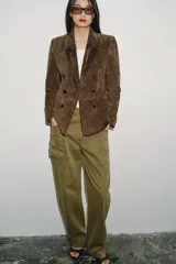 Blazer de ante color marrón, con cuello solapa, hombreras, manga larga y cierre frontal cruzado con botones. Cuenta con bolsillos delanteros de doble vivo.