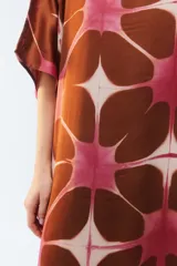 Kaftan maxi amplio de color amarillo, con escote redondo, mangas cortas y ruedo irregular. Presenta un diseño estampado a cuadros con efecto teñido.