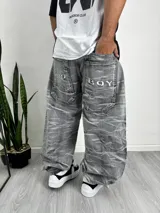 Pantalón de jean estilo baggy con lavado ácido en tono gris. Presenta un diseño holgado, bolsillos traseros amplios con el texto 'BAD BOY' bordado en blanco y costuras decorativas en los bolsillos.