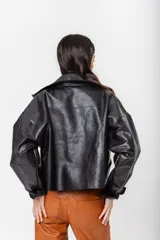 Chaqueta tipo bomber de cuero color suela con acabado rústico, cuello amplio, cierre frontal y mangas caídas de corte holgado.