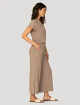Conjunto de dos piezas compuesto por una remera de manga corta con cuello redondo y frunces laterales ajustables, y un pantalón de corte ancho con cintura elástica y bolsillos laterales.