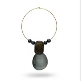 Collar tipo gargantilla con estructura metálica dorada, decorado con cuentas esféricas oscuras y un dije central compuesto por una pieza rectangular estriada y una pieza circular lisa, ambas en resina gris y negra.