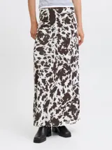 Pollera larga de corte recto confeccionada en tejido mesh con estampado animal print tipo vaca en tonos blanco y marrón oscuro. Presenta cintura elastizada y diseño fluido.
