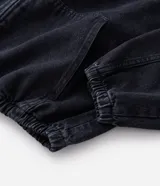 Campera tipo bomber confeccionada en tejido de jean, con cierre frontal de cremallera, capucha ajustable con cordones y bolsillos frontales. Presenta puños y cintura elásticos, ofreciendo un ajuste cómodo y un estilo urbano.