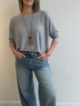 Sweater de punto fino y suave, color gris melange, con diseño amplio y relajado, escote redondo y mangas largas.