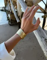 Brazalete rígido de diseño artesanal con textura irregular y acabado metálico, elaborado en bronce macizo.