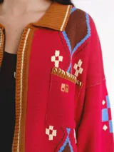 Campera tejida en jacquard con cierre frontal, cuello tipo polo y bolsillos delanteros. Diseño multicolor con estampado geométrico de rombos y detalles bordados a mano.