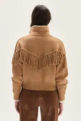 Bomber de tejido de punto color camel, con cuello de lana merino, cierre frontal, flecos decorativos en el frente y la espalda, y detalle de trenzas en las mangas.