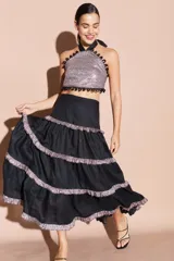 Falda larga de lino color tostado, con diseño de volados escalonados decorados con detalles brillantes en los bordes. Presenta una silueta fluida y cintura alta.