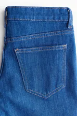 Jean de tiro bajo con diseño de cinco bolsillos, cierre frontal con botón y corte ajustado en la parte superior con piernas acampanadas.