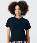 Remera negra de algodón con cuello redondo, manga corta y bordado frontal en relieve con forma de mariposa.
