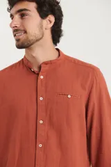 Camisa de cuello mao y manga larga, confeccionada en una mezcla de lino y algodón. Presenta un diseño de corte recto con botones en tono natural y un bolsillo pequeño en el pecho.