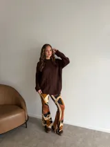 Buzo de punto en color beige, con diseño de trenzas verticales en el frente, cuello redondo y mangas largas con puños acanalados.