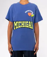 Remera de algodón gris oscuro con lavado especial, corte holgado y cuello redondo. Presenta un estampado frontal con la palabra "MICHIGAN" en amarillo neón con borde negro, y apliques decorativos en la parte superior: un corazón naranja, la palabra "NEWTONE" en arco y dos píldoras/pastillas de colores.