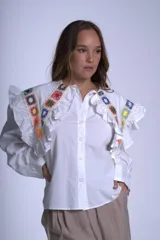 Camisa blanca de mangas largas con cuello claudine y bordado de crochet multicolor en cuello y hombros.