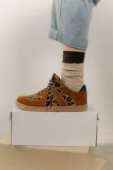 Zapatillas bajas color marrón con estampado animal print de leopardo, cordones grises y detalles en charol negro en el talón.