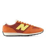 Championes urbanos New Balance modelo 471, con diseño inspirado en el running de los años 70. Presentan una combinación de colores naranja, terracota y amarillo, confeccionados con capas de ante, nylon y malla transpirable. Incluyen el logo N en amarillo, entresuela de EVA de perfil bajo y suela de goma con diseño de espiga.