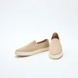 Zapatillas bajas sin cordones color beige de malla con suela blanca.