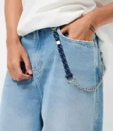 Pantalón de jean modelo skater, de corte holgado y tiro medio, con diseño de cinco bolsillos y detalle de cordón decorativo en la cintura.