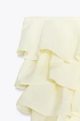 Top bandeau color crema con escote recto, hombros descubiertos y detalle de volantes en capas.